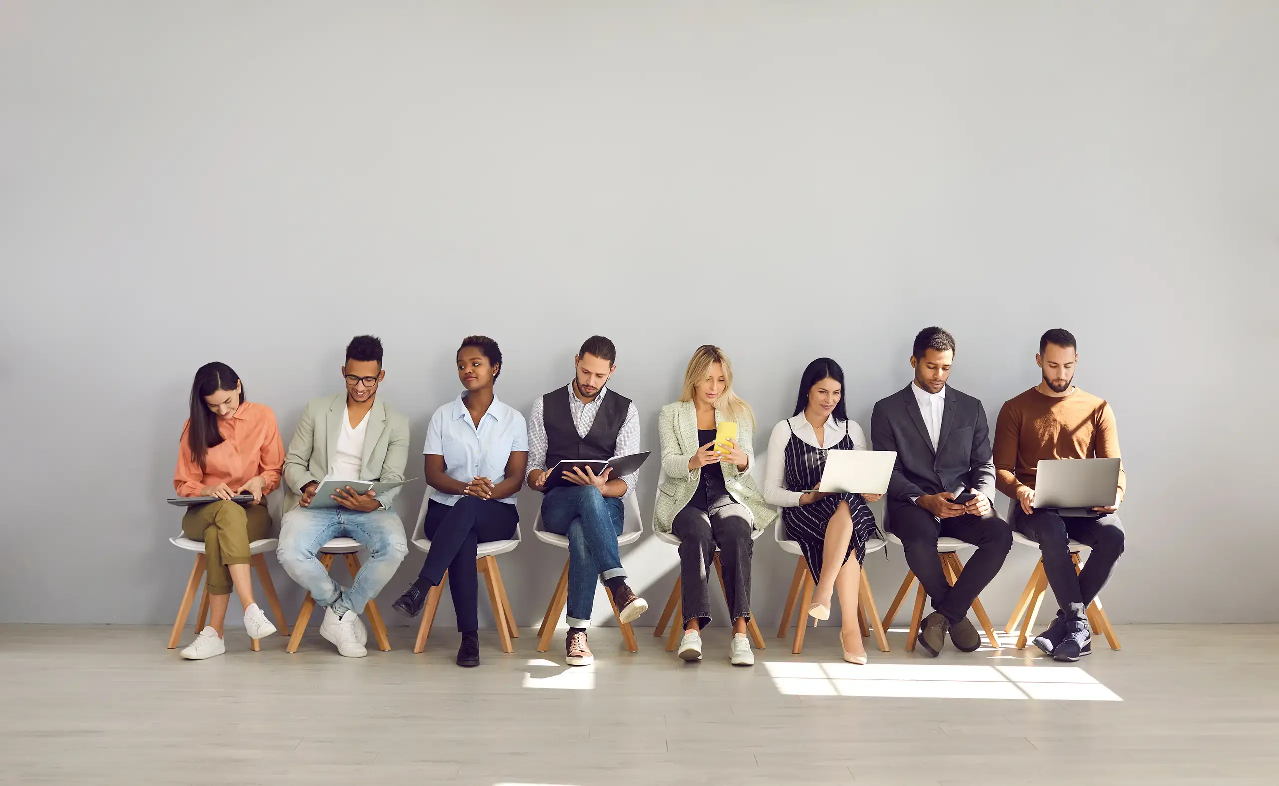 A group of people sitting in chairs waiting for job interviews.