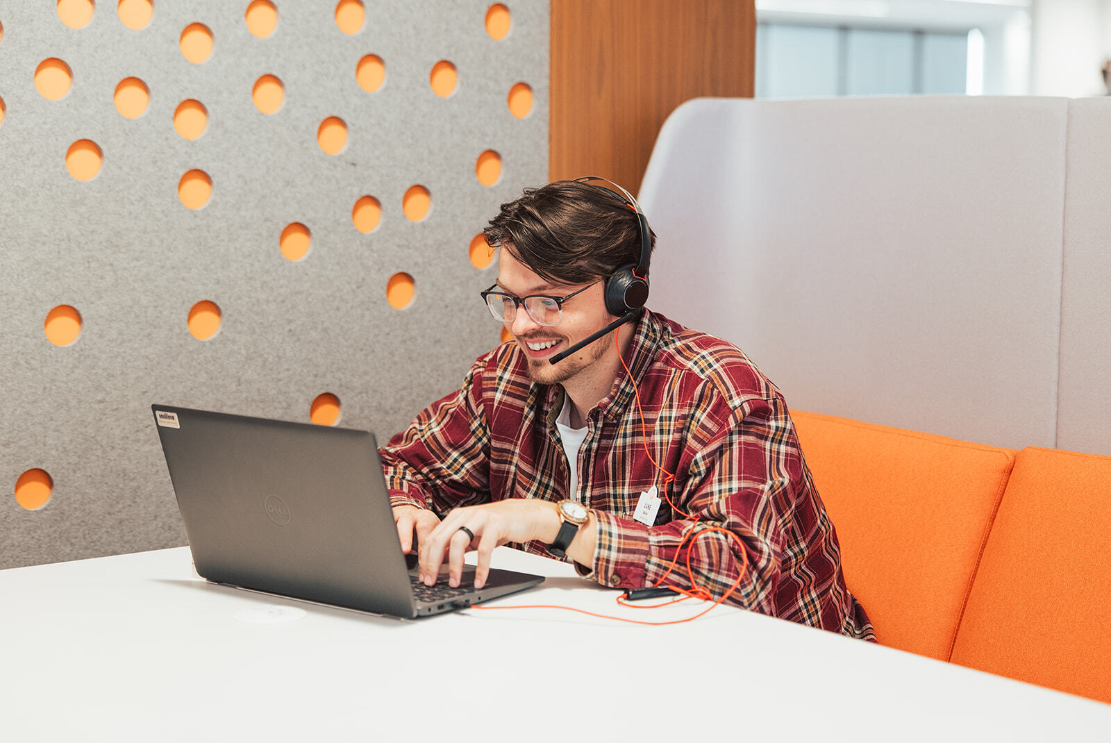 A man sitting at a booth table working on a laptop while on a video call.